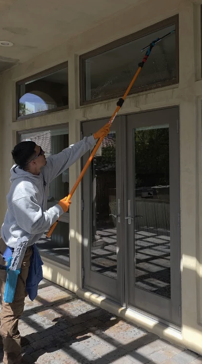 Real Clean technician pole-cleaning French door glass on a Las Vegas home