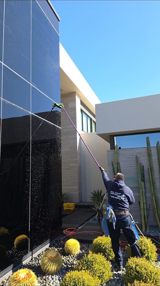 Technician cleaning exterior glass at a modern desert home